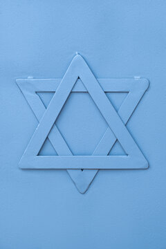 Metal Star of David (Magen David) Jewish symbol at blue fence metal surface, close up