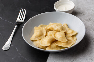 Traditional ukrainian dish vareniki served in a bowl with sour cream. Close up view of traditional Ukrainian food.