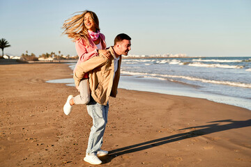 a happy young couple enjoying a piggyback ride on the beach