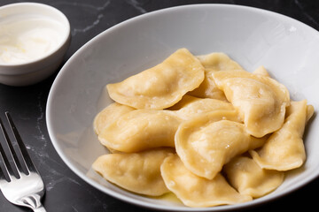 Traditional ukrainian dish vareniki served in a bowl with sour cream. Close up view of traditional Ukrainian food.