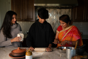 Mother teaching son how to cook, daughter looking over 