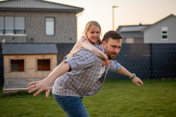 dad playing with his daughter in the backyard of the house.