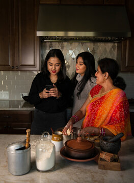 Daughters and mother looking at the cellphone in the kitchen 