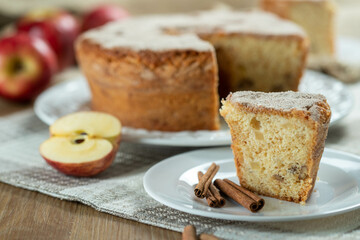 piece of Sponge cake or chiffon cake with apples so soft and delicious sliced ​​with ingredients: cinnamon, eggs, flour, apples on wooden table. Home bakery concept for background and wallpaper
