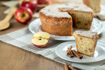 piece of Sponge cake or chiffon cake with apples so soft and delicious sliced ​​with ingredients: cinnamon, eggs, flour, apples on wooden table. Home bakery concept for background and wallpaper