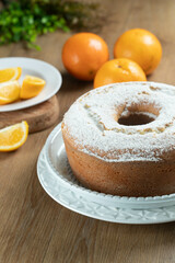 Moist orange fruit cake on plate with orange slices on wooden table. Delicious breakfast, traditional English tea time. Orange cake recipe.