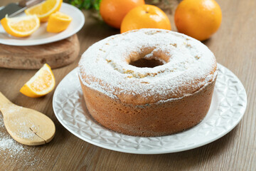 Moist orange fruit cake on plate with orange slices on wooden table. Delicious breakfast, traditional English tea time. Orange cake recipe.