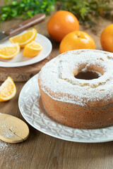 Moist orange fruit cake on plate with orange slices on wooden table. Delicious breakfast, traditional English tea time. Orange cake recipe.
