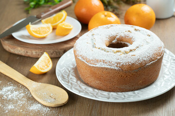 Moist orange fruit cake on plate with orange slices on wooden table. Delicious breakfast, traditional English tea time. Orange cake recipe.