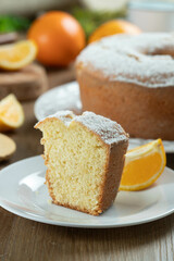 Close up piece of moist orange fruit cake on plate with orange slices on wooden table. Delicious breakfast, traditional English tea time. Orange cake recipe.