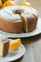 Close up piece of moist orange fruit cake on plate with orange slices on wooden table. Delicious breakfast, traditional English tea time. Orange cake recipe.