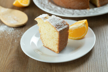 Close up piece of moist orange fruit cake on plate with orange slices on wooden table. Delicious breakfast, traditional English tea time. Orange cake recipe.