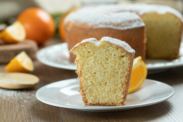 Close up piece of moist orange fruit cake on plate with orange slices on wooden table. Delicious...
