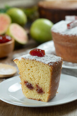 Close up piece of Brazilian corn cake made with a type of corn flour (Fuba) filled with guava paste. On a wooden party table. Typical sweets of the June festival. Cornmeal cake
