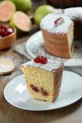 Close up piece of Brazilian corn cake made with a type of corn flour (Fuba) filled with guava paste. On a wooden party table. Typical sweets of the June festival. Cornmeal cake