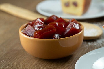 yellow can with guava jam cut into cubes with guavas in the background on wooden table