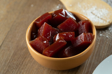 yellow can with guava jam cut into cubes with guavas in the background on wooden table