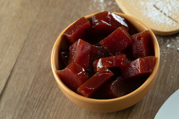 yellow can with guava jam cut into cubes with guavas in the background on wooden table