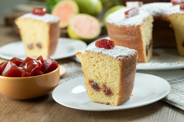 Close up piece of Brazilian corn cake made with a type of corn flour (Fuba) filled with guava paste. On a wooden party table. Typical sweets of the June festival. Cornmeal cake