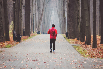 Lone runner on a dull morning in a foggy autumn park
