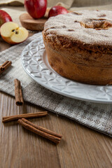 Obraz na płótnie Canvas Sponge cake or chiffon cake with apples so soft and delicious sliced ​​with ingredients: cinnamon, eggs, flour, apples on wooden table. Home bakery concept for background and wallpaper