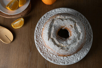 Moist orange fruit cake on plate with orange slices on wooden table. Delicious breakfast, traditional English tea time. Orange cake recipe.