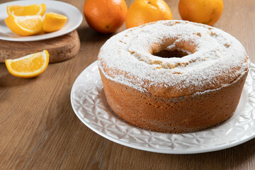 Moist orange fruit cake on plate with orange slices on wooden table. Delicious breakfast, traditional English tea time. Orange cake recipe.