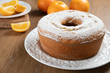 Moist orange fruit cake on plate with orange slices on wooden table. Delicious breakfast, traditional English tea time. Orange cake recipe.