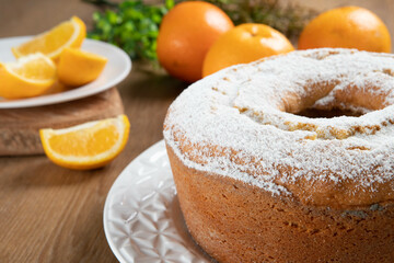 Moist orange fruit cake on plate with orange slices on wooden table. Delicious breakfast, traditional English tea time. Orange cake recipe.