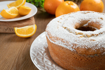 Moist orange fruit cake on plate with orange slices on wooden table. Delicious breakfast, traditional English tea time. Orange cake recipe.
