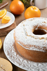 Moist orange fruit cake on plate with orange slices on wooden table. Delicious breakfast, traditional English tea time. Orange cake recipe.