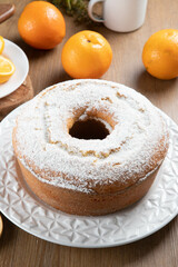 Moist orange fruit cake on plate with orange slices on wooden table. Delicious breakfast, traditional English tea time. Orange cake recipe.