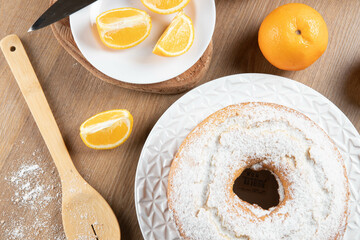 Moist orange fruit cake on plate with orange slices on wooden table. Delicious breakfast, traditional English tea time. Orange cake recipe. Top view