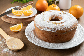 Moist orange fruit cake on plate with orange slices on wooden table. Delicious breakfast,...