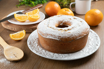 Moist orange fruit cake on plate with orange slices on wooden table. Delicious breakfast, traditional English tea time. Orange cake recipe.