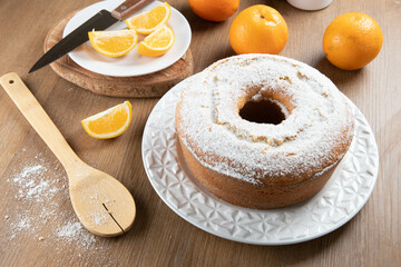 Moist orange fruit cake on plate with orange slices on wooden table. Delicious breakfast, traditional English tea time. Orange cake recipe.