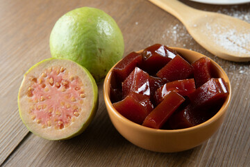 yellow can with guava jam cut into cubes with guavas in the background on wooden table