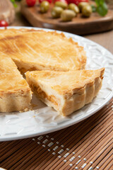 Close up piece of Chicken pie with cottage cheese, tomatoes, onion and olives on wooden table and white plate