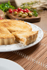 Close up piece of Chicken pie with cottage cheese, tomatoes, onion and olives on wooden table and white plate