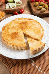 Chicken pie with cottage cheese, tomatoes, onion and olives on wooden table and white plate