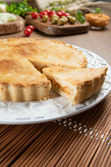 Close up piece of Chicken pie with cottage cheese, tomatoes, onion and olives on wooden table and white plate