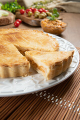 Close up piece of Chicken pie with cottage cheese, tomatoes, onion and olives on wooden table and white plate