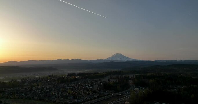 Aerial of a jet stream flying over Mount Rainier at sunrise.