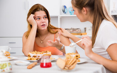 Obraz na płótnie Canvas Portrait of female talking with sad girl friend at the kitchen