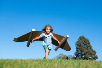 Boy child with wings at sky imagines a pilot and dreams of flying. Kids adventure, children freedom and imagination concept.