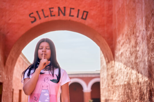 Turista latina señalizando silencio parada bajo el arco Silencio del monasterio Santa Catalina en Arequipa