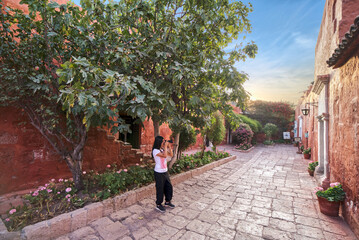 Fototapeta na wymiar Turista latina fotografiando la calle Málaga del monasterio Santa Catalina en Arequipa