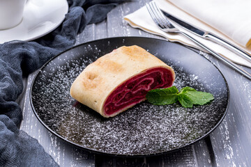 Cherry strudel with mint on black plate