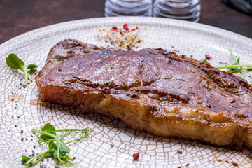 juicy Striploin Steak on grey plate on dark stone table macro close up