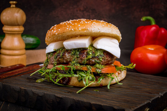 Burger Caprese With Meat Patty,  Mozzarella Cheese And Tomatoes With Aragula On Dark Board